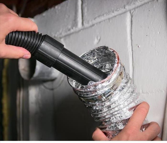 Vacuum cleaning a flexible aluminum dryer vent hose, to remove lint and prevent fire hazard.